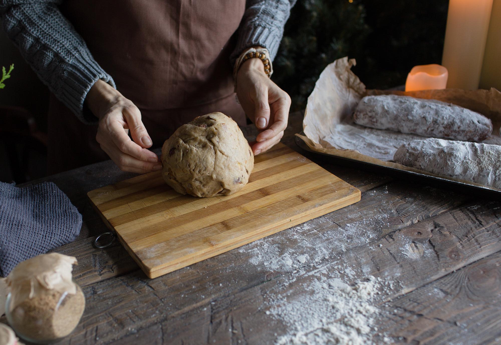 Close-up of hands kneading dough on floured board